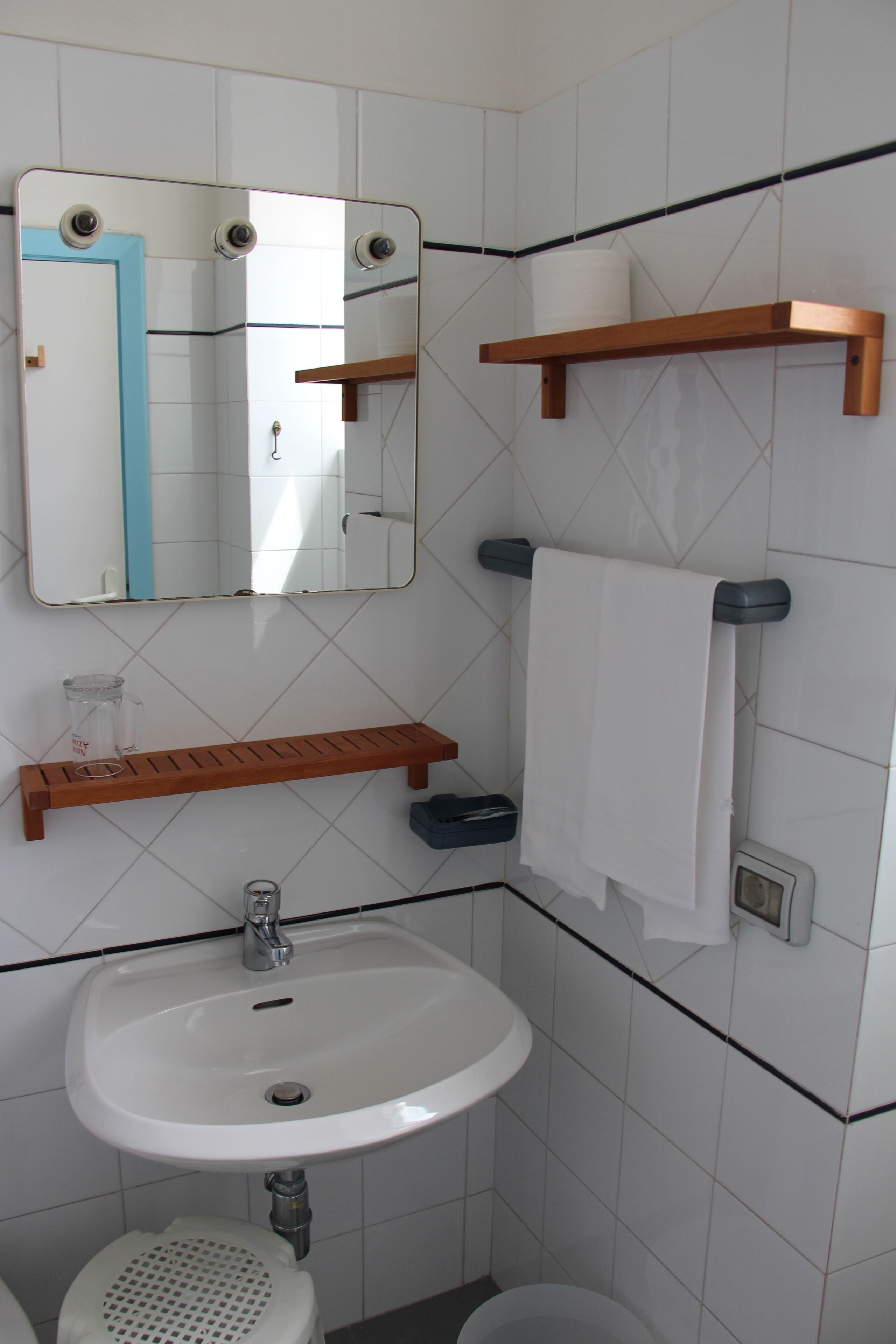 A bathroom with a white sink, a mirror, a towel rack, and a toilet.