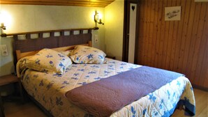 A bed with a floral quilt, a brown throw blanket, and a wooden headboard. - Spacious apartment for 6 in Le Grand-Bornand (Le Grand-Bornand)