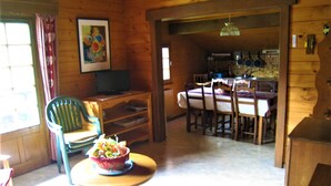 A wooden interior with a dining area, a television on a shelf, and a table with a basket of fruit. - Spacious apartment for 6 in Le Grand-Bornand (Le Grand-Bornand)