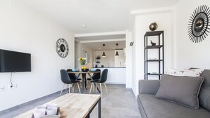 A modern living room with a grey sofa, a wooden coffee table, and a dining area with a table and chairs. - SW Bailen Beautiful views (Málaga)