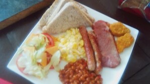 Une assiette de petit-déjeuner comprenant des toasts, des œufs, des saucisses, des haricots et une salade.