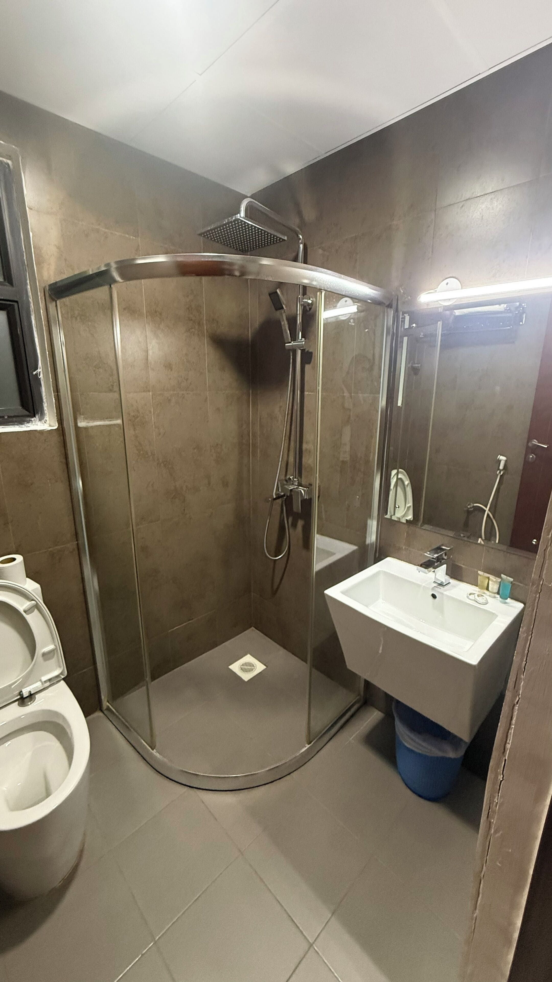 Une salle de bain moderne avec une douche à parois de verre, un lavabo blanc et des toilettes.