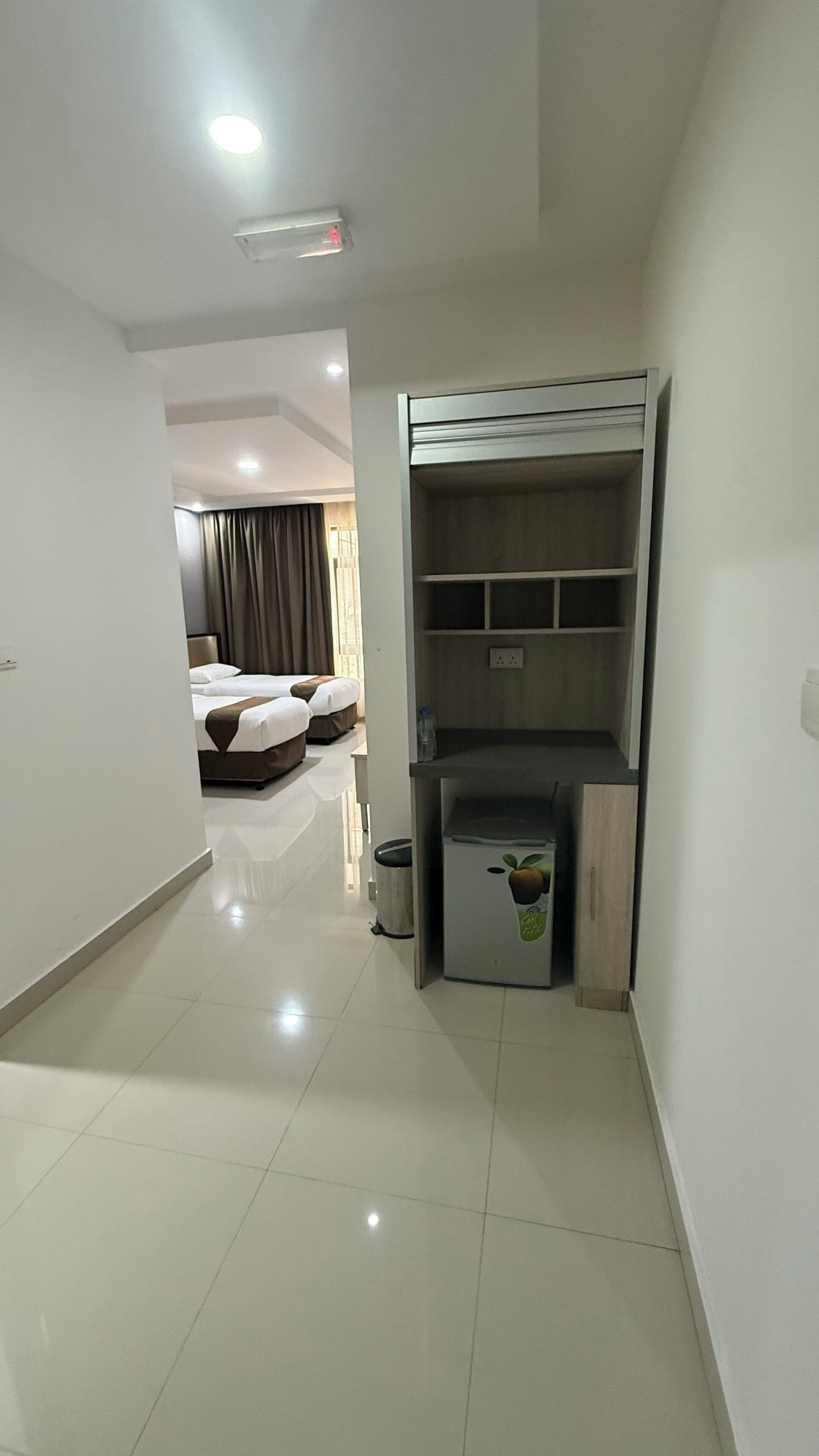 Habitación de hotel con literas, un escritorio y un cubo de basura pequeño.