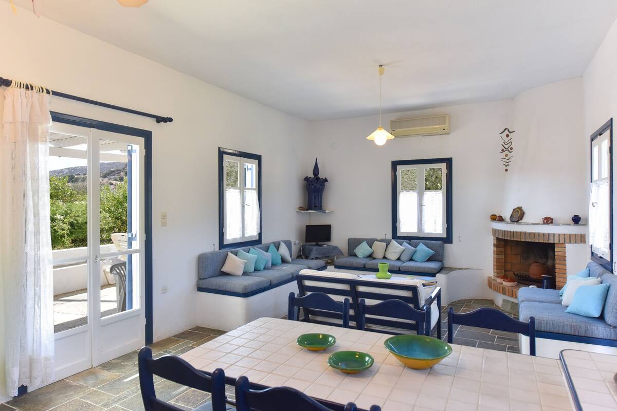 A spacious living area with a sofa set, a dining table, and a fireplace.