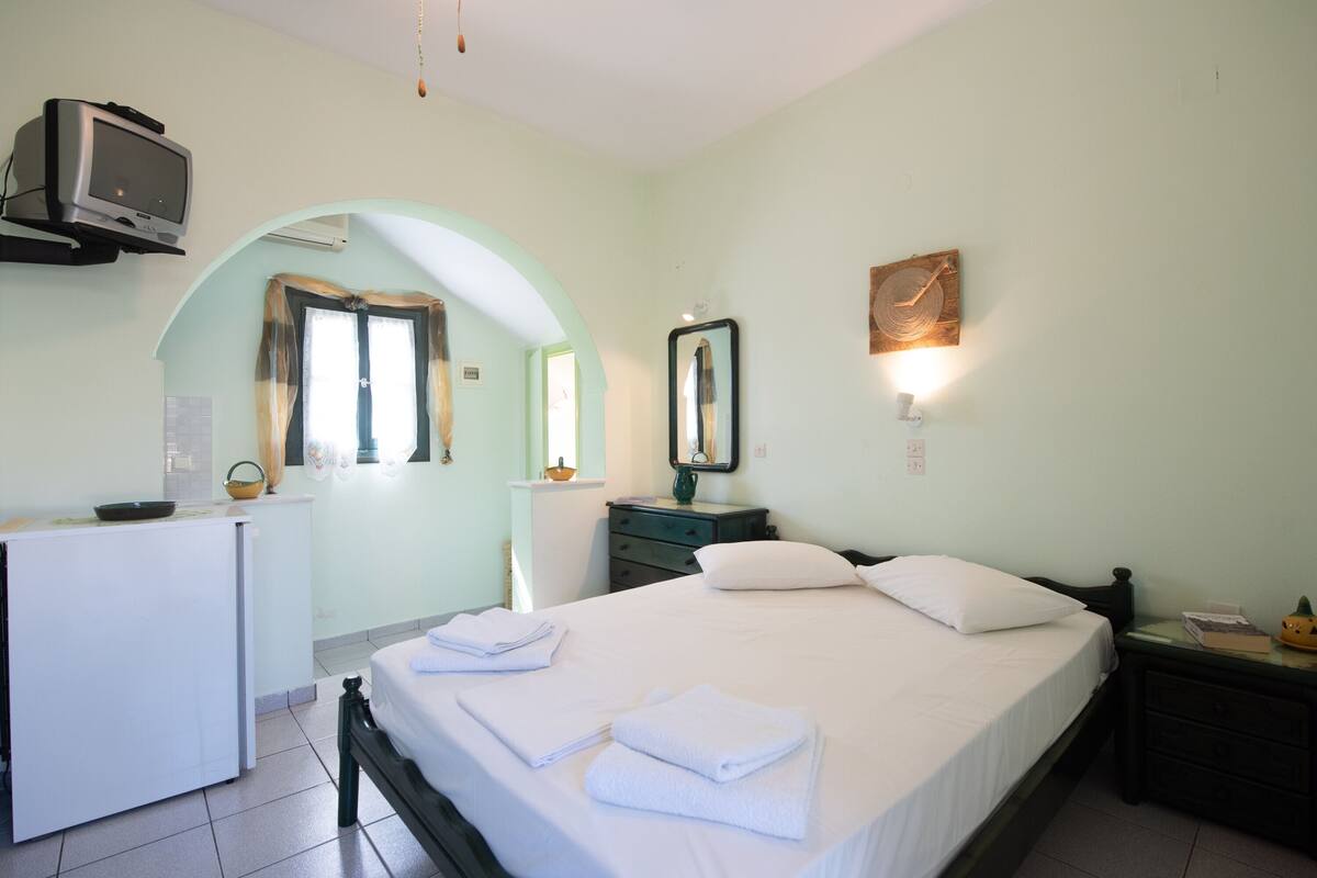 A hotel room with a bed, a desk, a television, and a mirror.