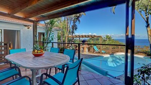 Une terrasse couverte avec une piscine, des sièges d’extérieur et une vue sur l’océan.