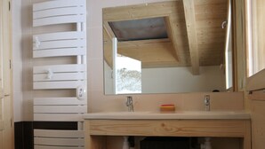 Ein Badezimmer mit einem Holzbadezimmer-Möbel, einem Spiegel und einem Fenster über dem Waschbecken.