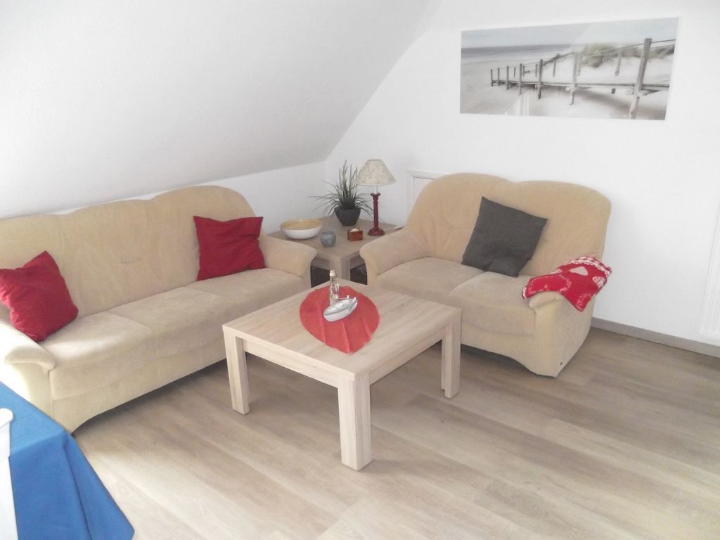 Ein Wohnzimmer mit zwei beigefarbenen Sofas, einem Holztisch als Couchtisch und einem kleinen Beistelltisch mit Lampe und Dekoration.