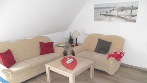 A living room with two beige sofas, a wooden coffee table, and a small side table with a lamp and decorative items.