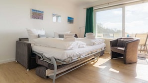 Une chambre à coucher avec un lit, une chaise et une fenêtre avec des rideaux.