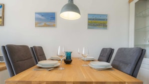 Une table à manger avec six chaises, un vase bleu et six verres à vin disposés sur la table.