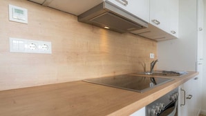 Une cuisine moderne dotée d’un plan de travail en bois, d’un évier en acier inoxydable et d’un four encastré.