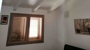 A room with a sloped ceiling, a window with blinds, and a framed picture on the wall.