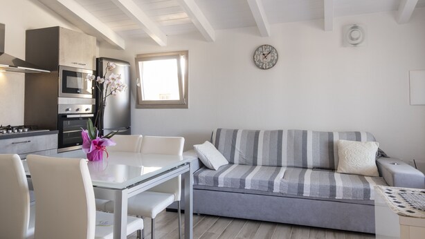 A modern kitchen with a dining area, a sofa, and a clock on the wall.