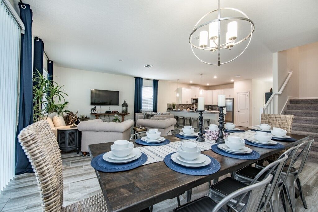 A modern dining area with a wooden table set for a meal, surrounded by wicker chairs.