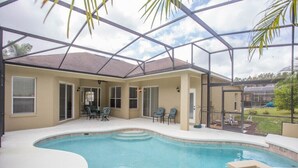 Une piscine entourée de parois en verre, un espace extérieur aménagé avec des sièges et une terrasse couverte.