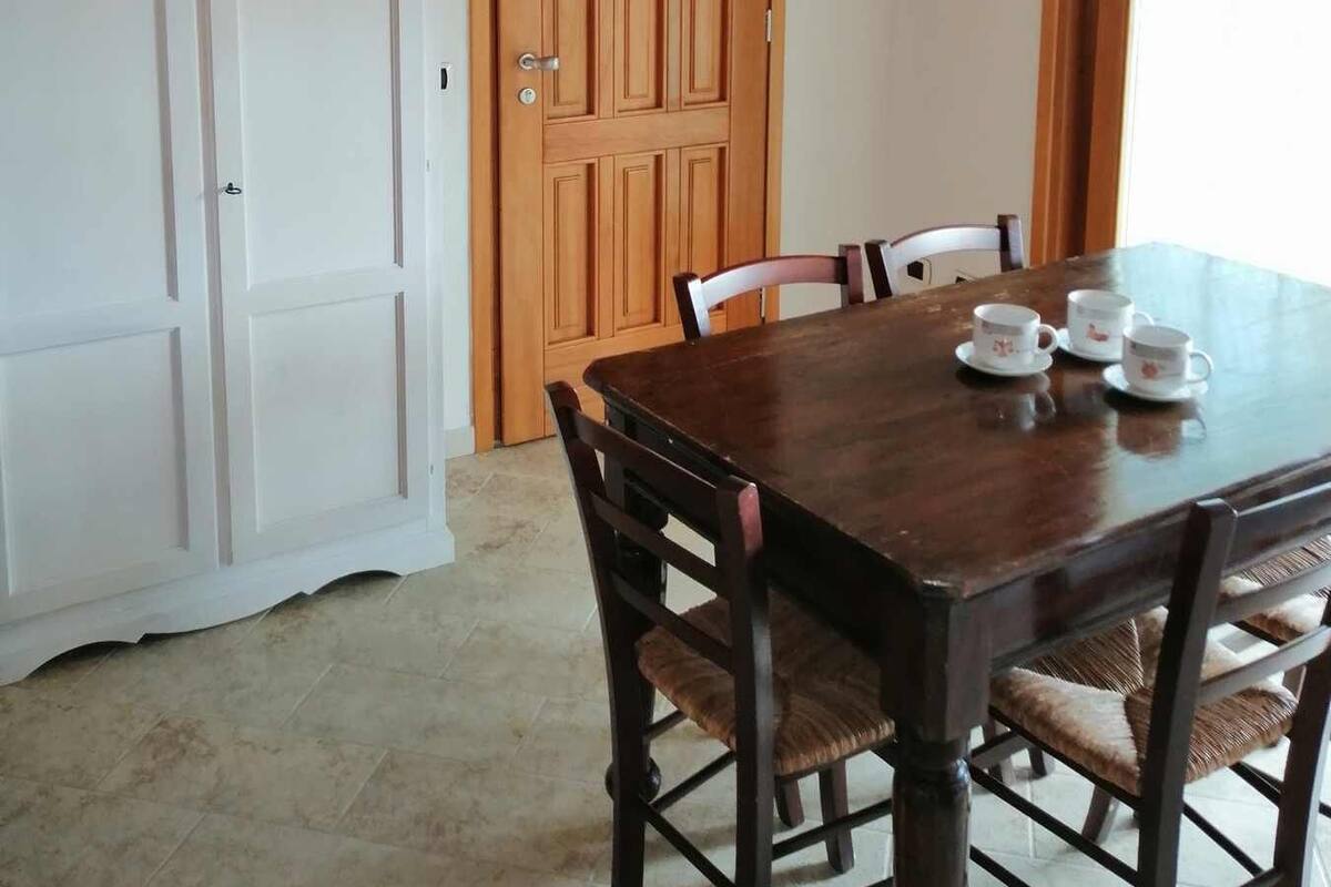 A dining area with a wooden table and chairs, a white cabinet, and a wooden door.