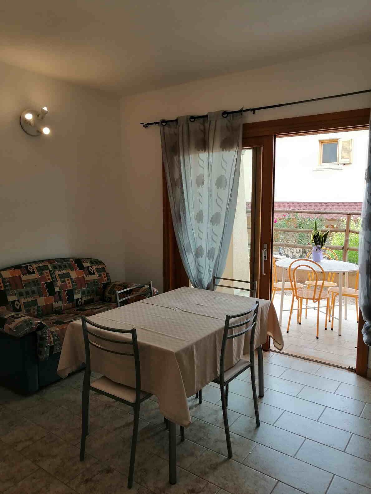 Un coin repas avec une table et des chaises, un canapé à motifs et une vue sur l’extérieur.