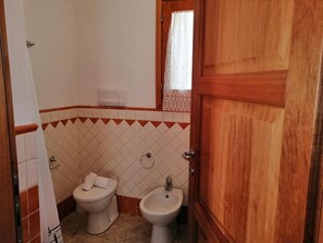 Une petite salle de bain avec des toilettes, un bidet et une porte en bois.