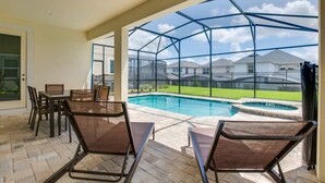 An outdoor patio with a pool, chairs, and a glass enclosure. - 1791spp 5 Bedroom Townhouse by RedAwning (Kissimmee)