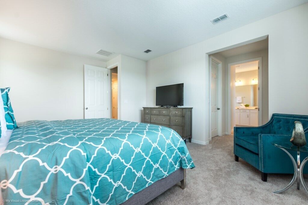 A bedroom with a bed, a TV, a dresser, and a chair.