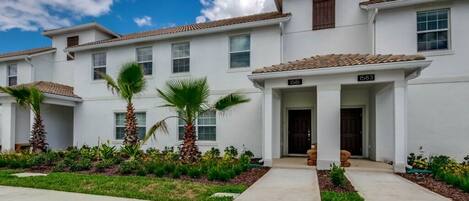 A two-story residential building with a tiled roof and white exterior walls.