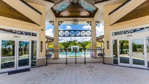 A covered entrance to a building with the number 3901, a pool, and a view of greenery. - 2619ca 10 Bedroom Villa by Redawning (Kissimmee)