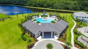 A golf course with a swimming pool, surrounded by lush greenery and a lake. - 2619ca 10 Bedroom Villa by Redawning (Kissimmee)