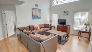 A spacious living room with a sectional sofa, a flat-screen TV, and a dining table. - Privacy Pool Area In This Beautiful ! 4 Bedroom Home by RedAwning (Haines City)