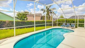 A swimming pool with a white deck, surrounded by a white fence, and a view of houses and greenery in the background. - Privacy Pool Area In This Beautiful ! 4 Bedroom Home by RedAwning (Haines City)