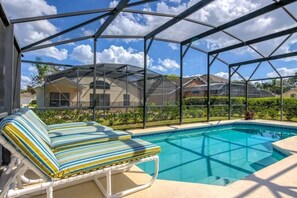 A pool area with a covered seating area and a view of a house in the background. - Large Pool With Game Room! 5 Bedroom Home by RedAwning (Haines City)