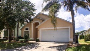 A single-story house with a garage, surrounded by trees and a well-maintained lawn. - South Facing Pool Great For Families! 4 Bedroom Home by RedAwning (Haines City)
