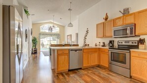 Une cuisine moderne avec des armoires en bois, des appareils en acier inoxydable et un grand îlot central.