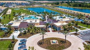 An aerial view of a resort with a swimming pool, multiple buildings, and a parking area.