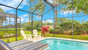 A pool area with lounge chairs and a glass enclosure. - Gated Community Southern Dunes Golf 4 Bedroom Home by RedAwning (Haines City)