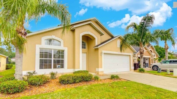 A single-story house with a garage, palm trees, and a well-maintained lawn. - Gated Community Southern Dunes Golf 4 Bedroom Home by RedAwning (Haines City)