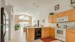 A modern kitchen with wooden cabinets, a built-in dishwasher, a microwave, and an oven. - Gated Community Southern Dunes Golf 4 Bedroom Home by RedAwning (Haines City)