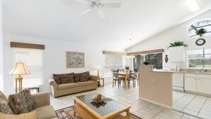 A spacious living room with a sofa, coffee table, and dining area with chairs.