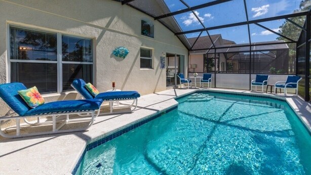 A swimming pool with lounge chairs and a covered patio area.