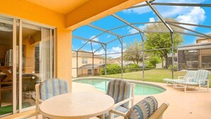 Ein überdachter Patio mit Pool, Stühlen und Tisch.