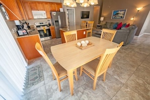 Una cocina moderna con armarios de madera, electrodomésticos de acero inoxidable y una zona de comedor con mesa y sillas de madera.