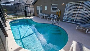 A swimming pool with lounge chairs and a covered area.
