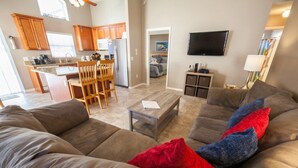 A modern living room with a large sectional sofa, a coffee table, and a TV mounted on the wall.