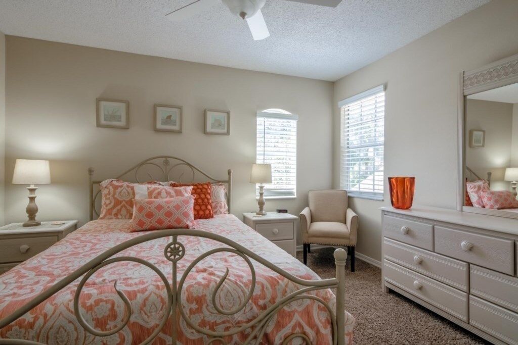 A bedroom with a bed, nightstands, a dresser, a chair, and a window with blinds.