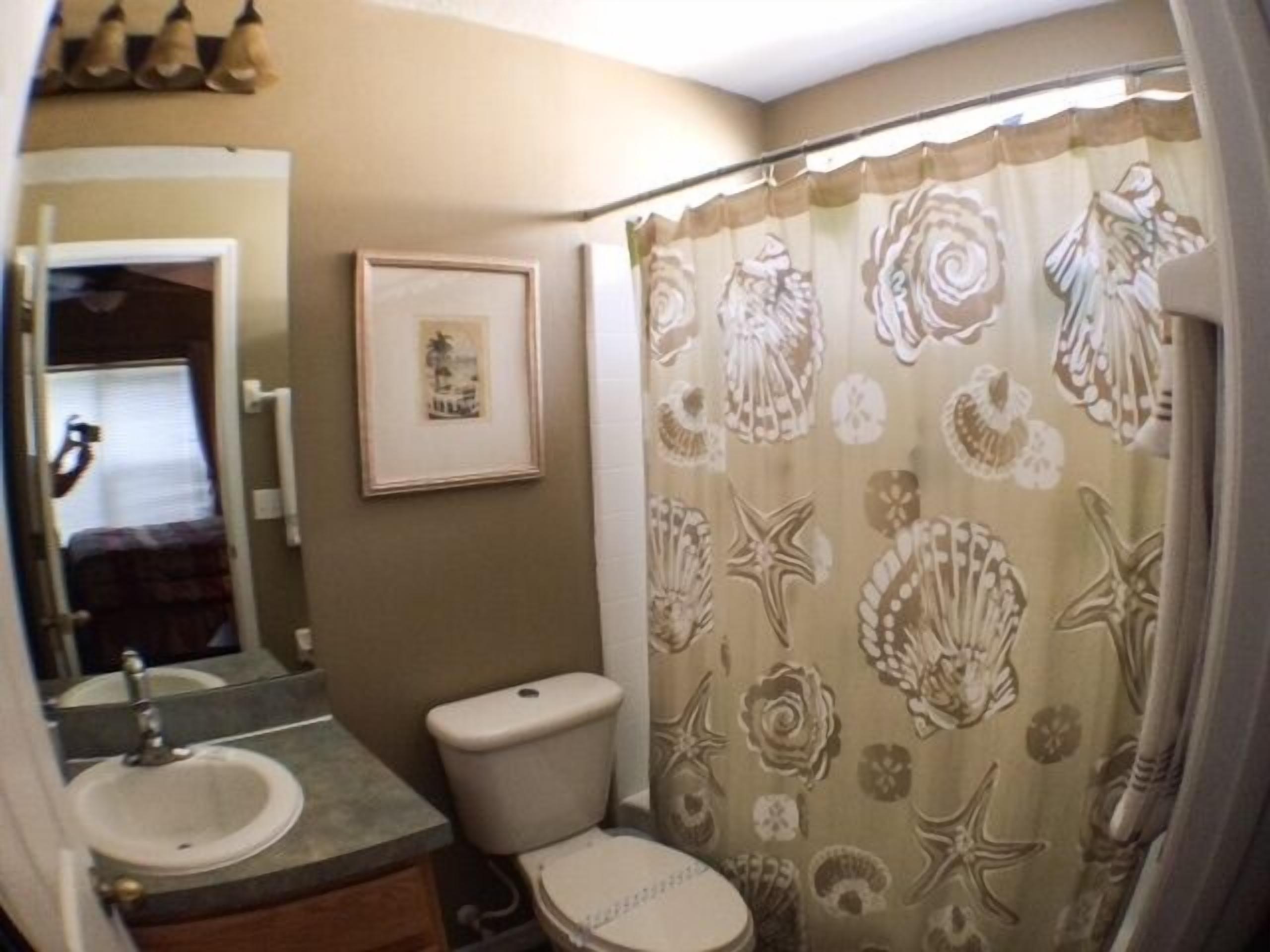 A bathroom with a sink, toilet, and shower curtain with a floral pattern.