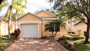 A single-story house with a garage, a paved driveway, and a well-maintained lawn with a palm tree. - Perfect For Your Florida Vacation! 3 Bedroom Home by RedAwning (Haines City)