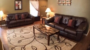 A living room with two dark leather sofas, a wooden coffee table, and a patterned rug. - Perfect For Your Florida Vacation! 3 Bedroom Home by RedAwning (Haines City)