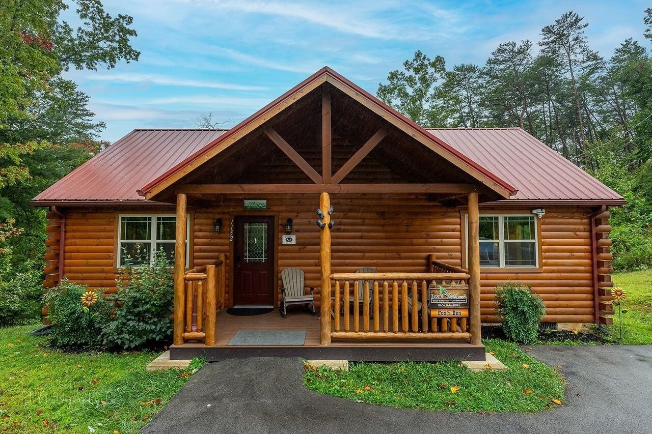 A log cabin with a porch, a front door, and a sign indicating 'Fox's Den.'