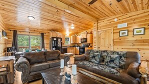 A cozy log cabin interior with a living room, kitchen, and dining area. - Foxes' Den Cabin with Private Hot Tub and Arcade Game by RedAwning (Pigeon Forge)