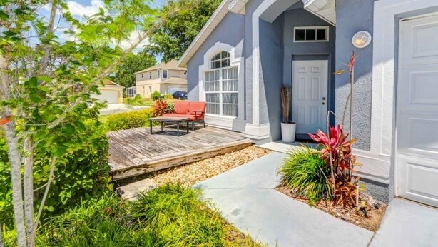 Une maison d’habitation dotée d’un patio couvert, d’une porte d’entrée et d’un petit jardin.